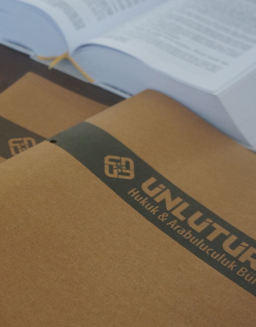 Ünlütürk Hukuk ve Arabuluculuk Bürosu antetli dosya klasörleri ve açık bir kanun kitabı